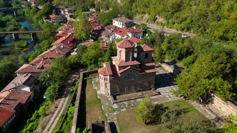 Drone orbit around the Church of Saint Demetrius of Salonica in Veliko Tarnovo, showcasing its historic stone structure and serene surroundings.