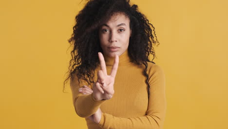 una mujer afroamericana segura de sí misma sobre un fondo naranja.