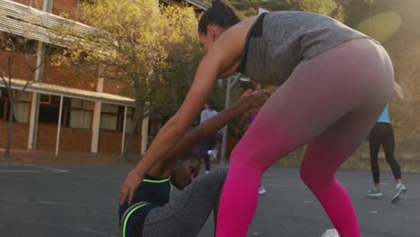 Diverse-female-basketball-team-playing-match,-helping-each-other