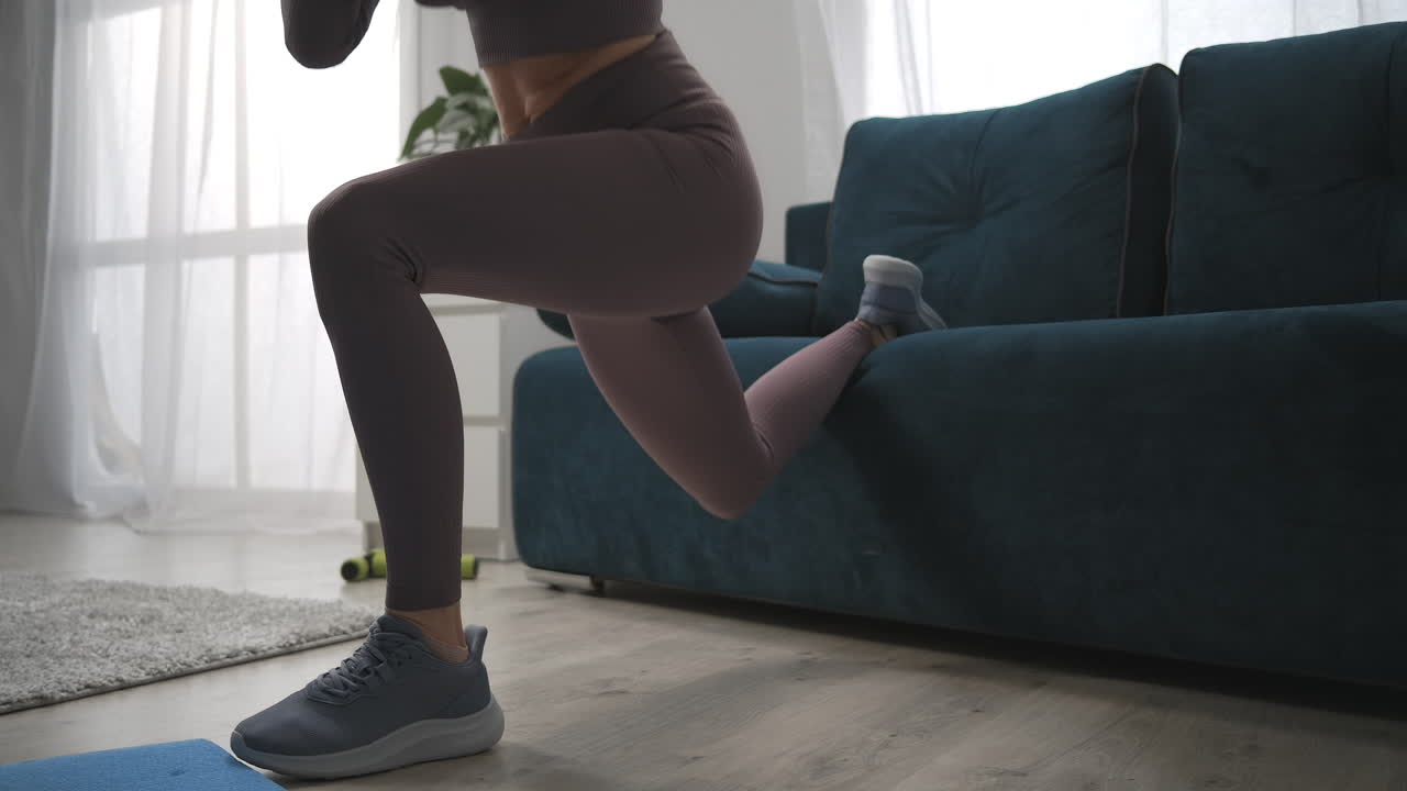nahaufnahme der schlanken beine einer jungen frau, die zu hause trainiert. sportliche dame macht übungen für beine, muskeln, weibliche sportliche person.