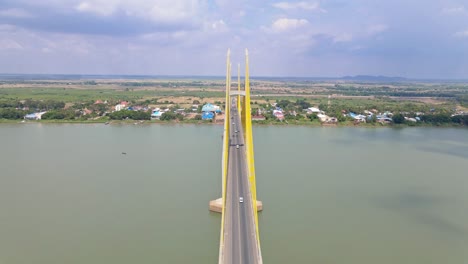 aerial flyover neak loeung bridge with driving cars crossing calm mekong river during sunny day