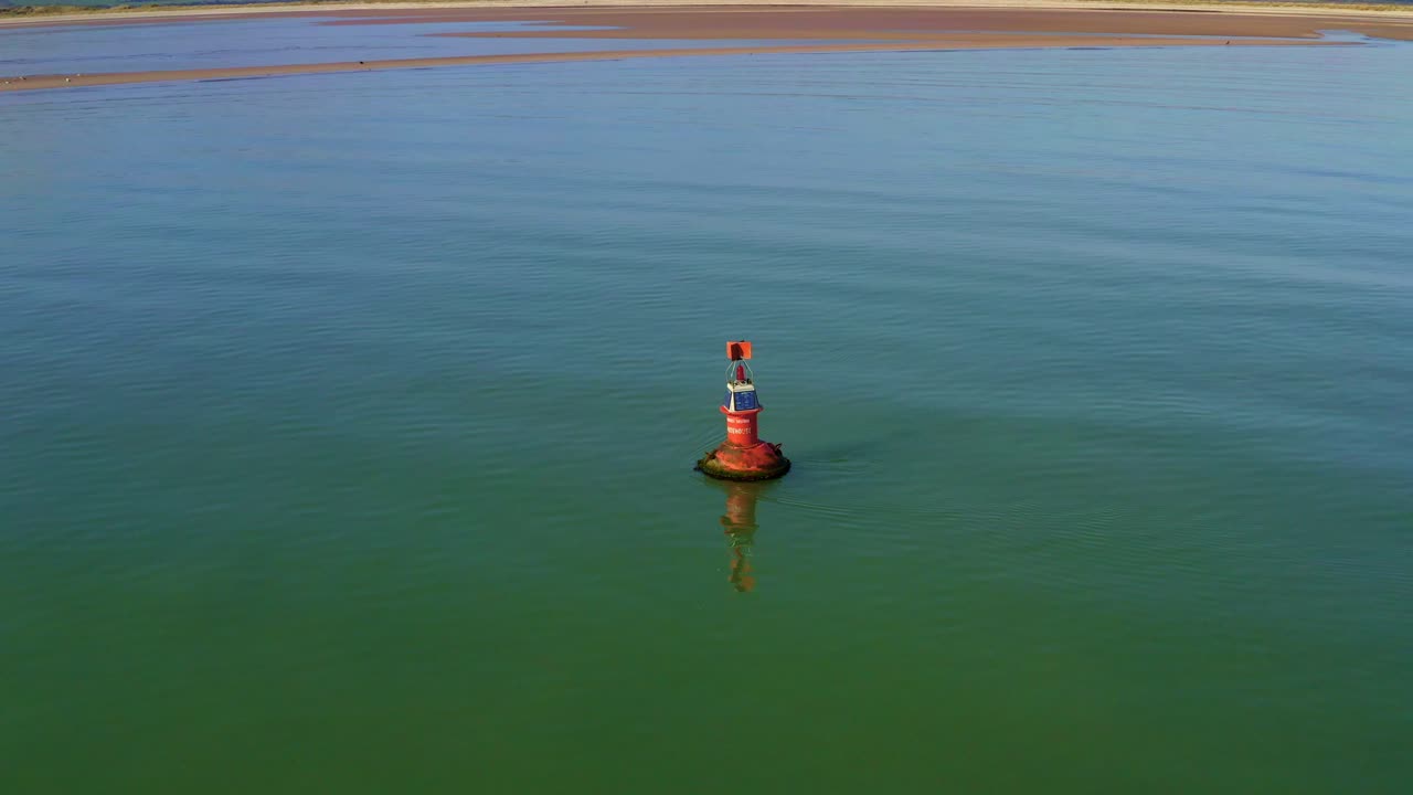 Aerial orbit shot of Marine Navigation Buoy on sea surface on sunny day