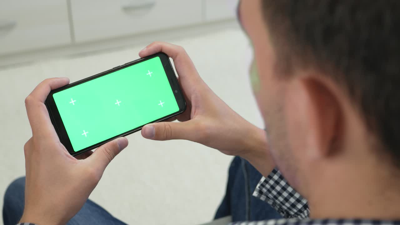 크로마 키 스크린으로 스마트폰을 보는 성인 남성의 측면 시각