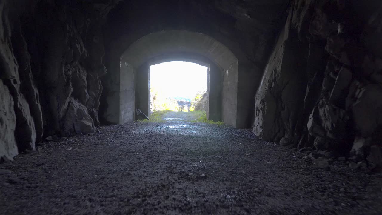 Walking forwards in dark cave with a bright opening in the middle