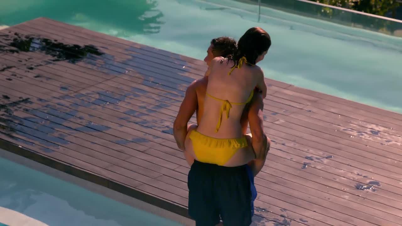 Man giving his pretty girlfriend a piggy back poolside