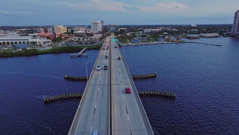 aerial tracking shot of driving cars on bridge crossing caloosahatchee river at dusk - fort myers, florida, usa