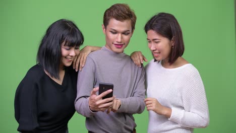 three happy asian friends using phone together