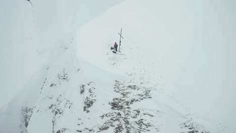 Alpine-skiers-are-stand-on-the-snow-covered-mountain-top-near-the-cross