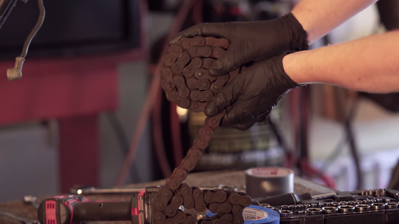 cerca de las manos rodando la cadena durante el desmontaje de la motocicleta