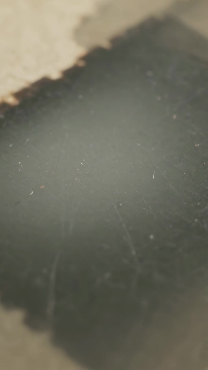 Vídeo vertical: Câmera panorâmica deslizando para cima e para a direita sobre uma mesa mostrando uma mancha escura com uma vieira bege.