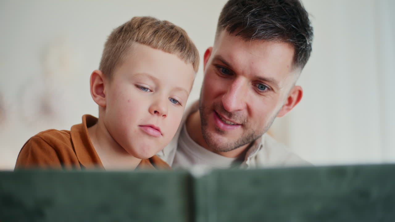 un niño pequeño y su padre miran fotos familiares