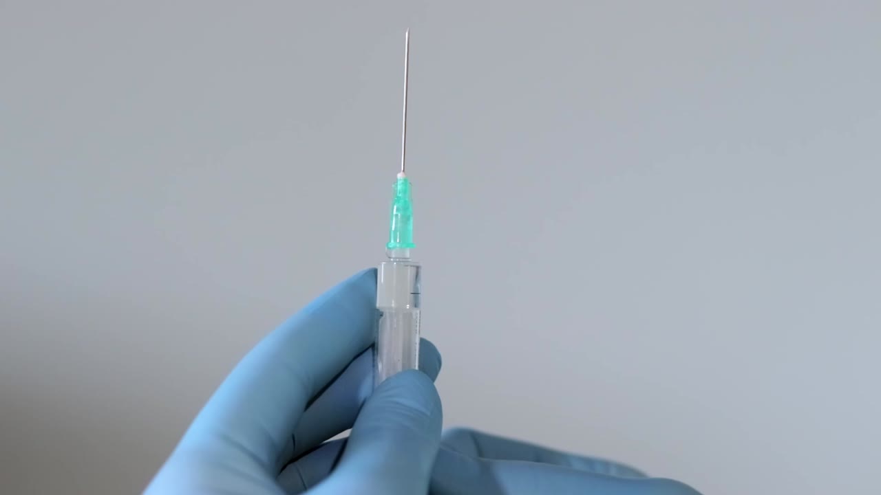 primer plano extremo de las manos del médico usando guantes quirúrgicos y lanzando aire de una jeringa a través de una aguja afilada en un fondo aislado