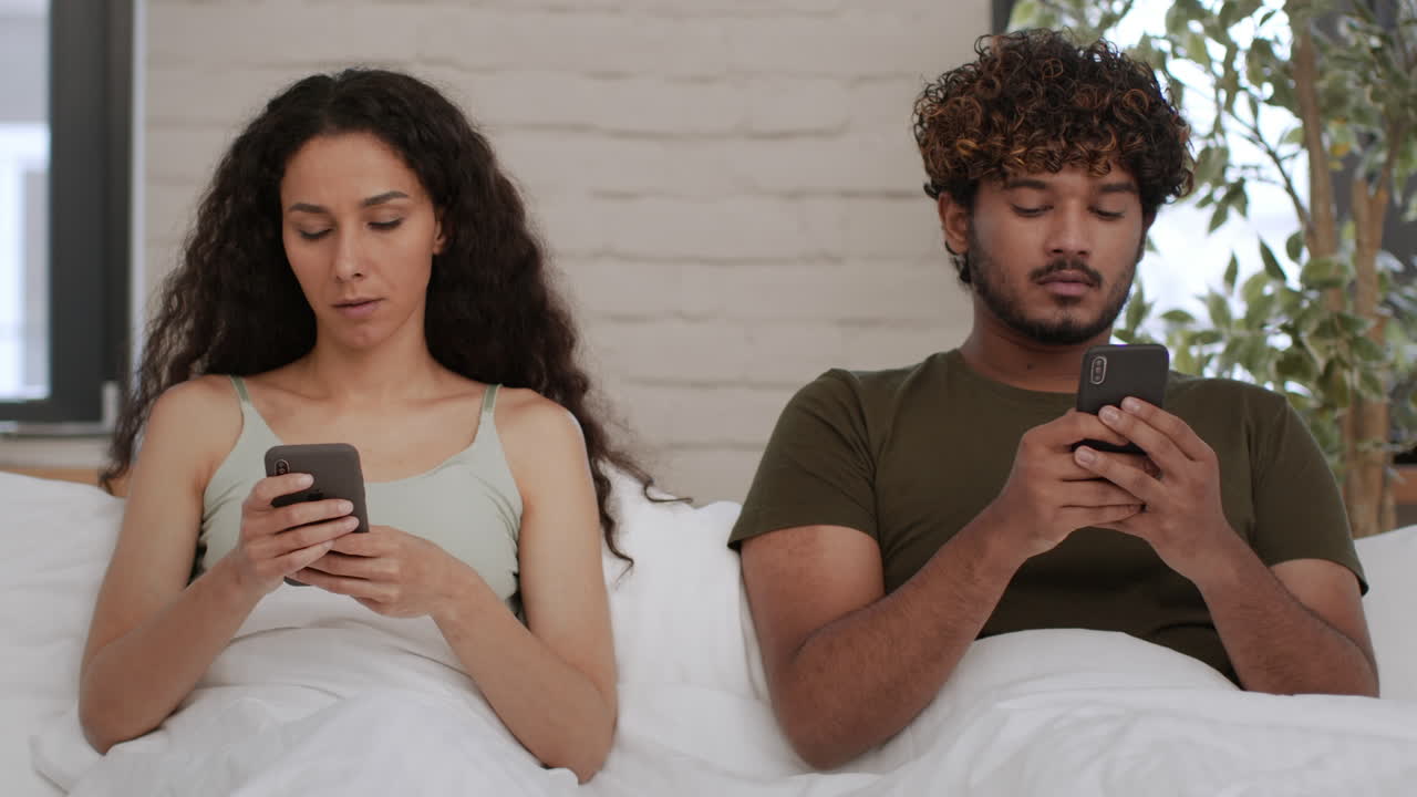 Couple in Bed, Distracted by Phones