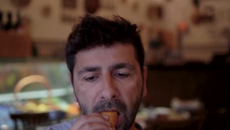 young-man-sits-in-a-Lisbon-restaurant,-savoring-a-delicious-cod-fritter-and-smiling-with-contentment,-capturing-the-joy-of-enjoying-traditional-Portuguese-cuisine