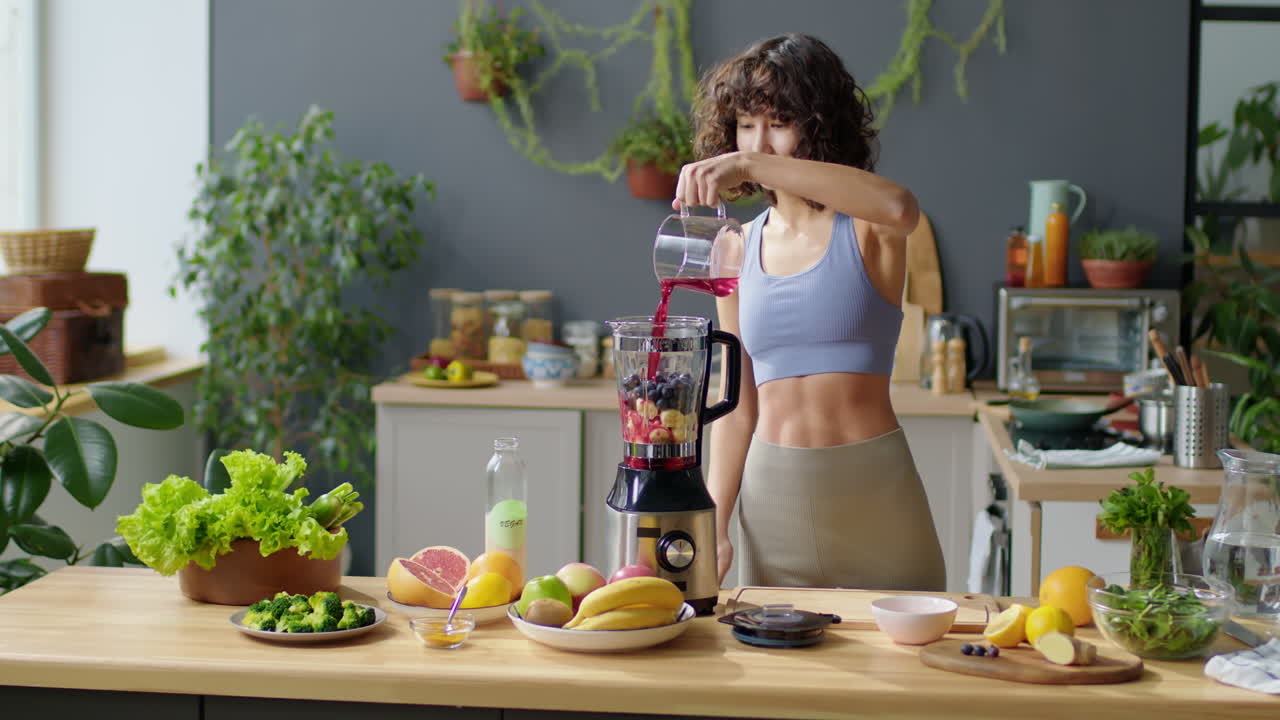 Fit Woman Preparing Smoothie in Kitchen Blender