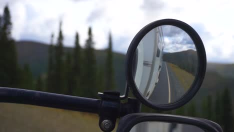 vista estática mirando un espejo, mientras conduce en la parte superior de la carretera mundial, dentro de un camión de trabajo, en el desierto de alaska, en un día nublado, en alaska, estados unidos