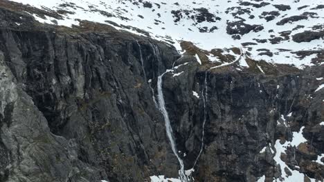 Tverrelva-waterfall-falling-down-towards-trollstigen-road-during-early-spring---Aerial