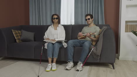 front view of blind friends sitting on a sofa in a flat