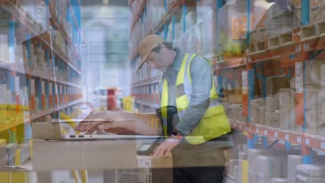 animation of caucasian businessman using laptop over worker scanning boxes in warehouse