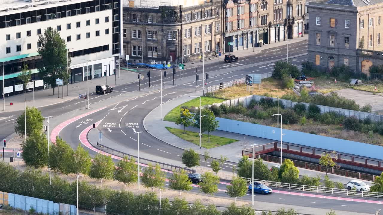 Daytime aerial view of vehicles moving along curved urban road with historic buildings in Dundee