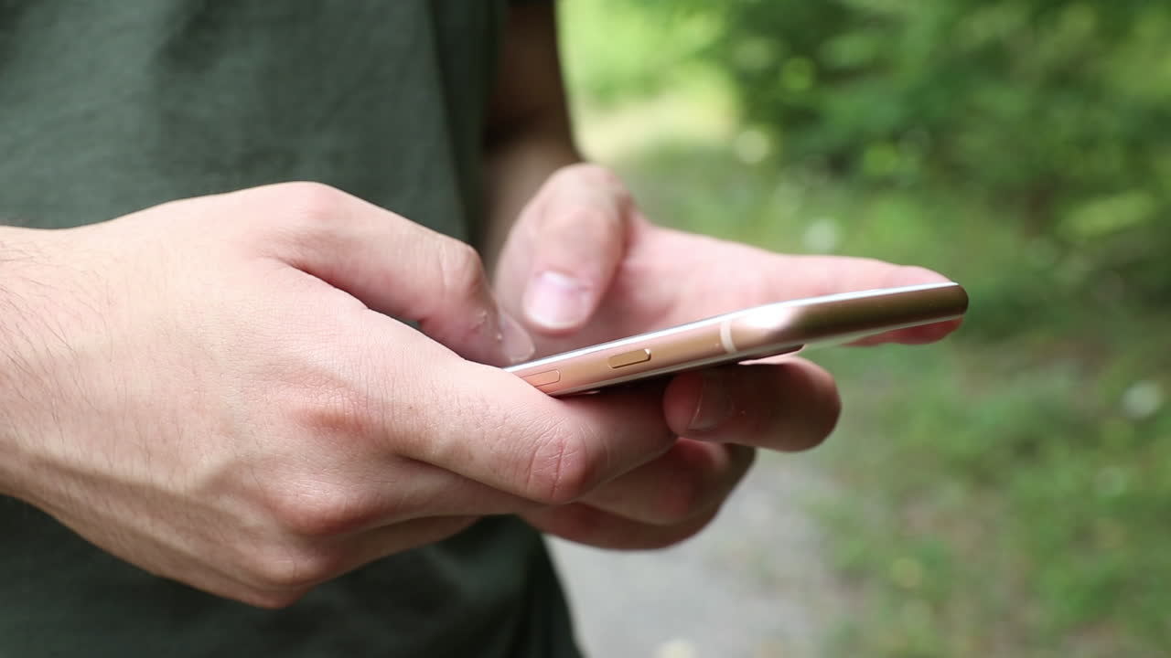 adolescente masculino escribiendo en un teléfono en un bosque