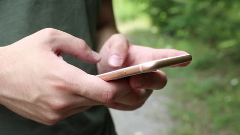 Adolescente-Masculino-Escribiendo-En-Un-Teléfono-En-Un-Bosque