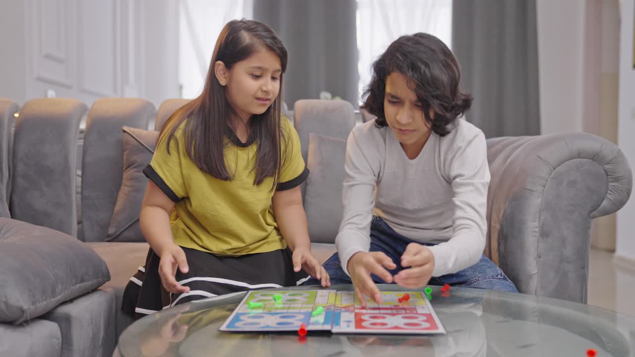 un niño indio abandona el juego de ludo cuando su hermana está a punto de ganar.