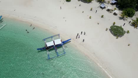 bajando por el aire descendiendo sobre el bote de banca y los turistas de la playa