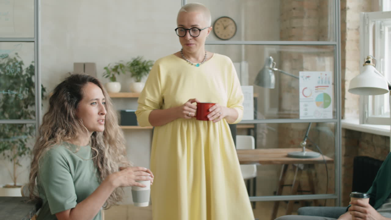 Gruppo eterogeneo di colleghi che conversano durante la pausa caffè in ufficio
