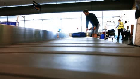 commuters taking their baggage from baggage carousel