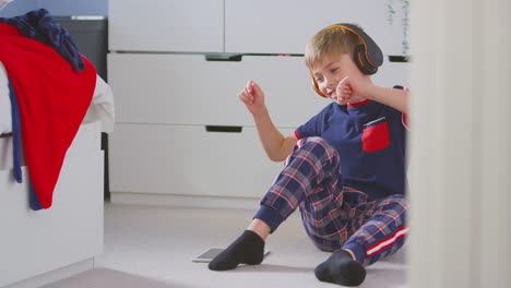 Niño-En-Casa-En-El-Dormitorio-Usando-Auriculares-Inalámbricos-Escuchando-Música-En-Una-Tableta-Digital