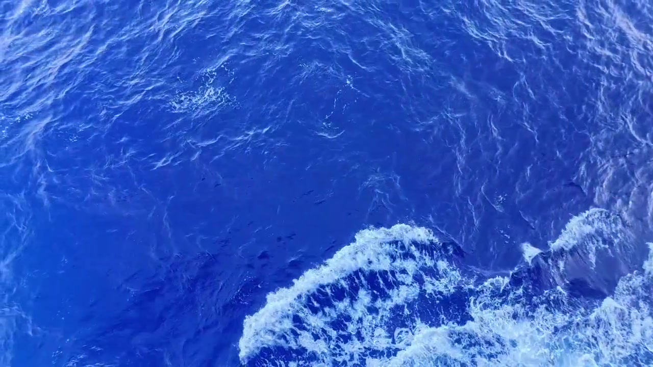Vue aérienne de l'océan bleu profond aux vagues douces et à l'écume
