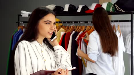 beautiful female shop assistant talking on the phone, working at the clothing store