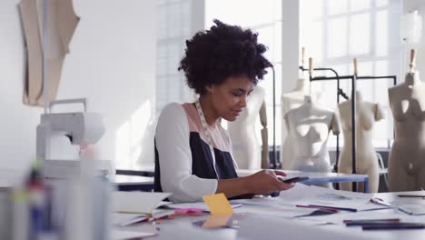 Mixed-race-woman-on-smartphone-in-fashion-office