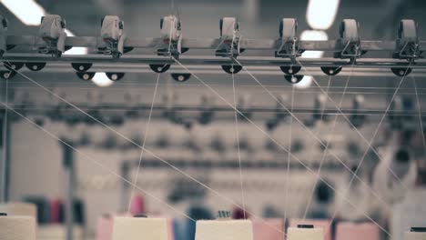 view of spools of white thread on knitting device
