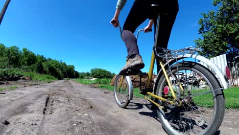 young woman riding vintage bicycle along a rural road in a village. slow motion