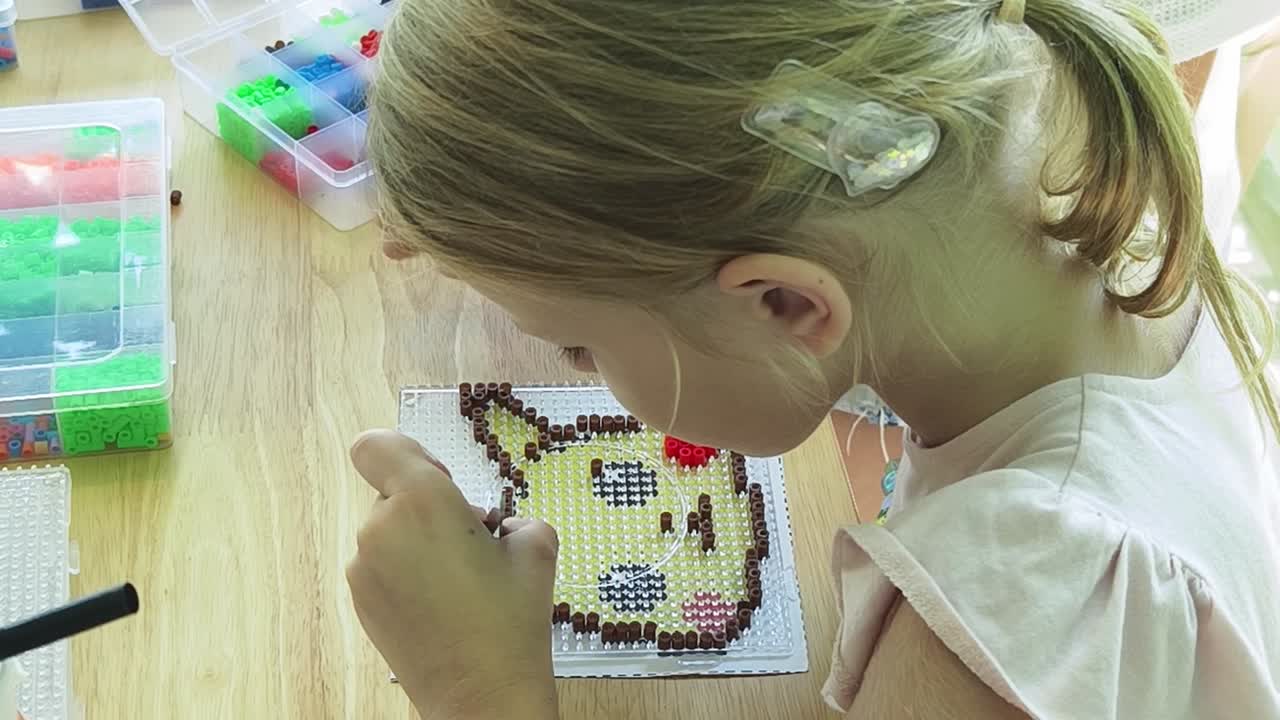 chica haciendo pixel art con cuentas