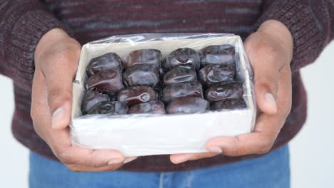 persona que sostiene una caja de dátiles