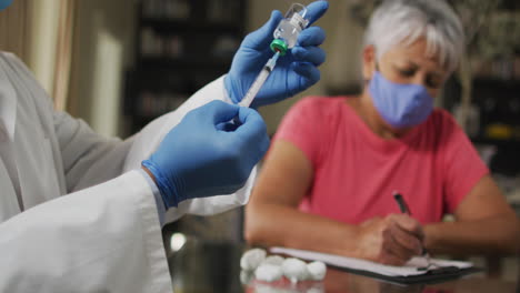 male doctor visiting senior biracial woman preparing vaccination