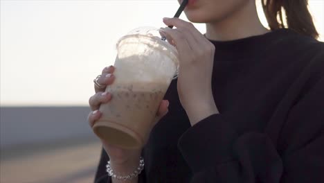 woman enjoying an iced coffee outdoors at sunset