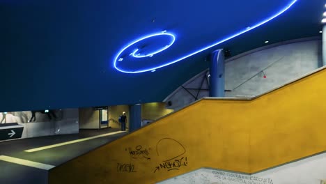 blue neon lights illuminate subway escalator area