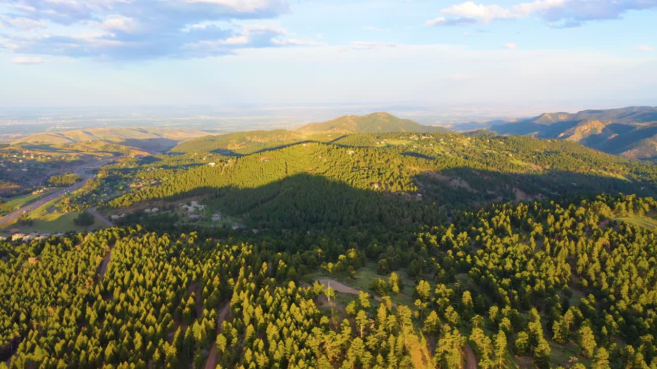 Majestic cinematic drone footage of Colorado Rocky Mountains at golden hour, golden sunlight over alpine meadows, cliffs, pine forests, and panoramic vistas, perfect 4K aerial nature video for travel