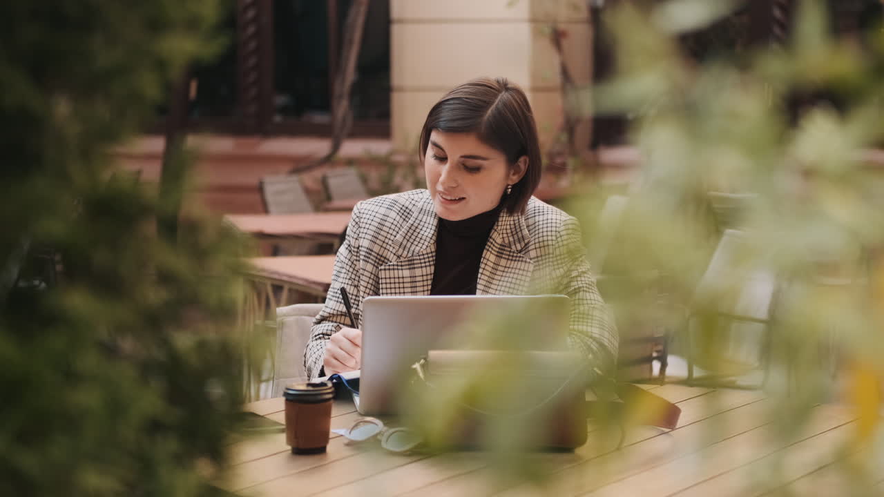 Businesswoman working on laptop in cafe outdoor.