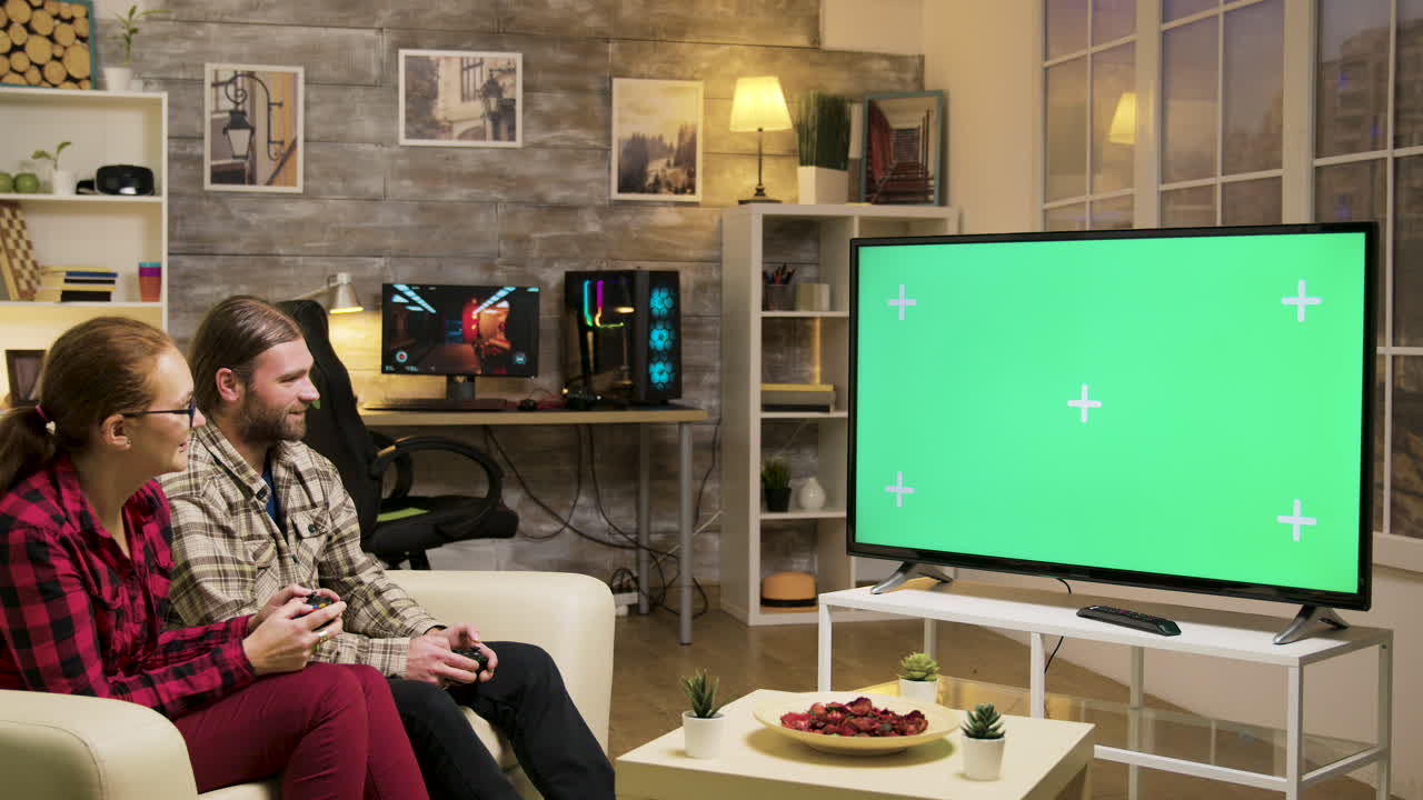 Couple playing video games on a TV with green screen in living room