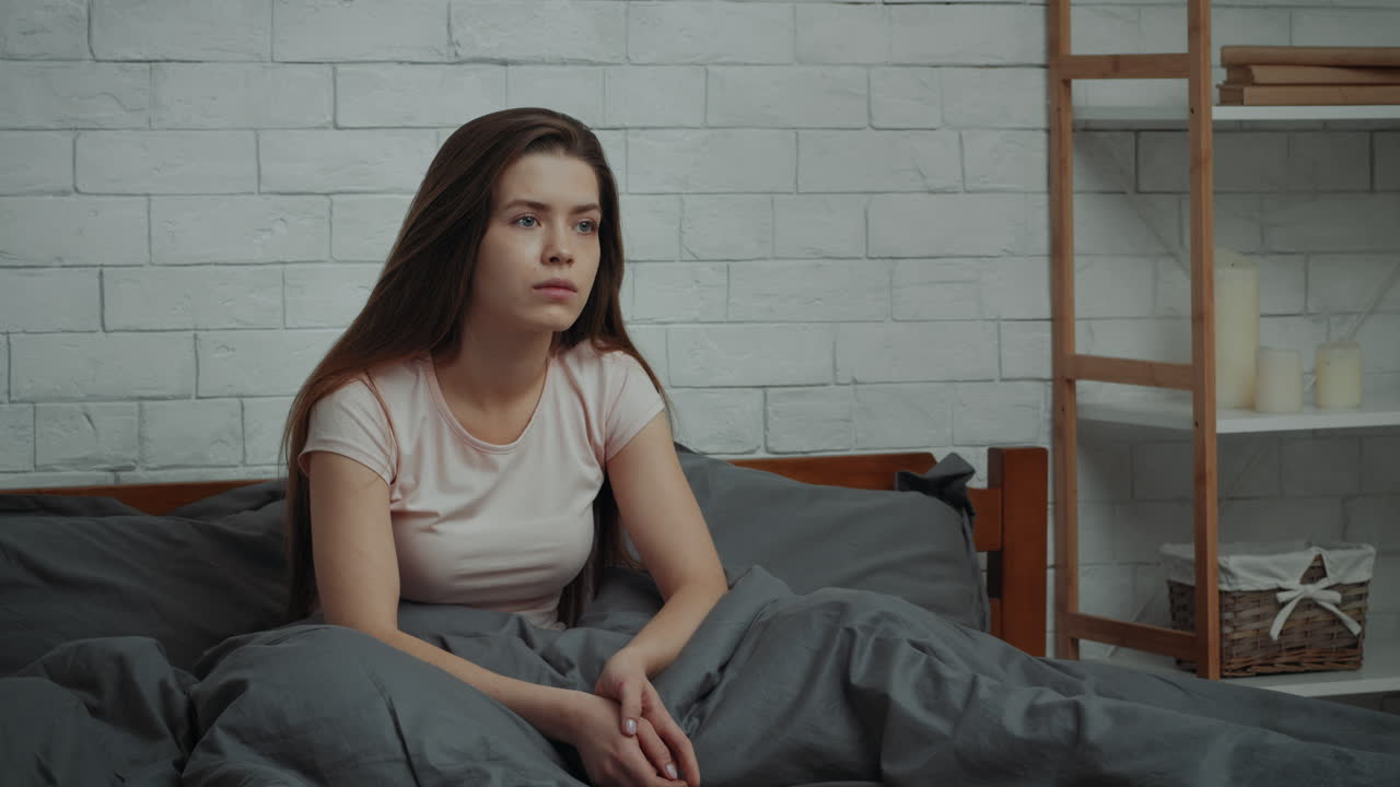 Woman sitting in bed looking sad