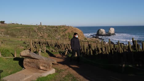 man walking with face mask on pandemic trip new way of traveling in punta de lobos surf point in chile with face mask in new normal of chile healthy covid free near chilean cactus pichilemu H frame ra