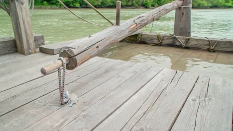 Long-oar-used-to-steer-and-paddle-wooden-raft-boat,-close-up-orbit