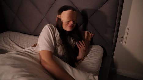 Attractive-young-woman-getting-to-bed-late-at-night-with-a-sleeping-mask