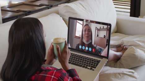 Mixed-race-woman-on-laptop-video-chat-having-coffee-at-home