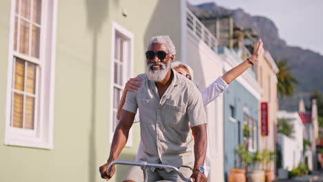 happy senior couple riding a bicycle on a city street